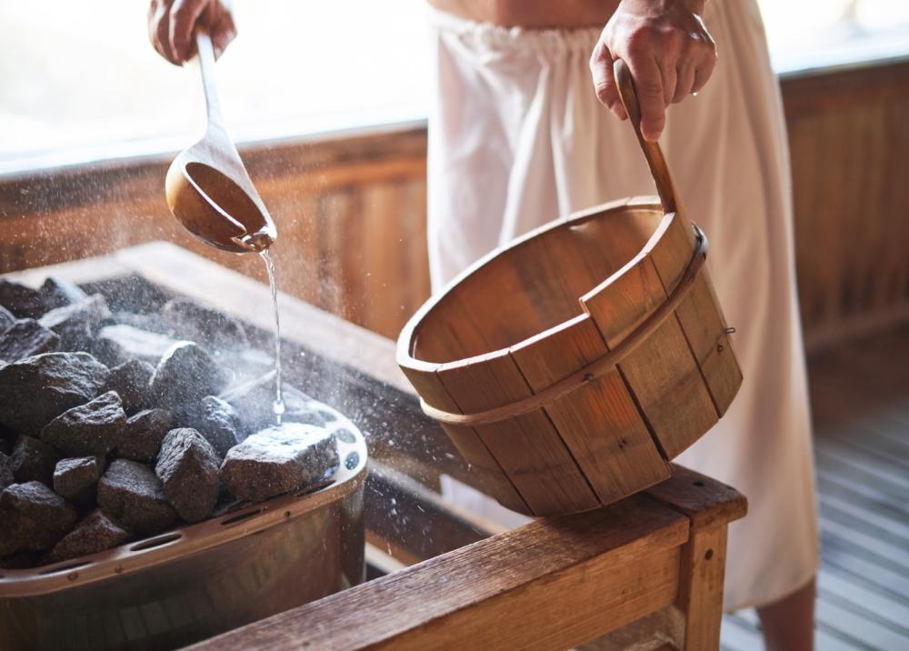 Homme versant de l'eau dans un sauna
